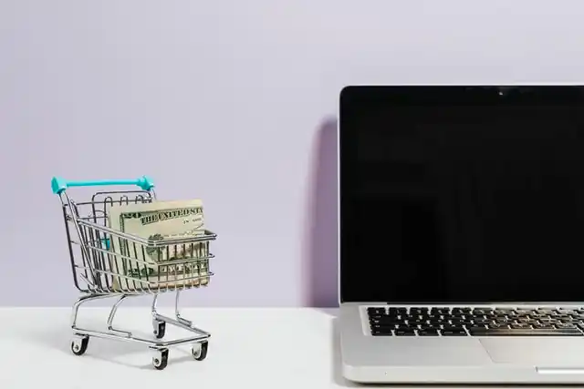 miniature cart beside a laptop indication online purchasing