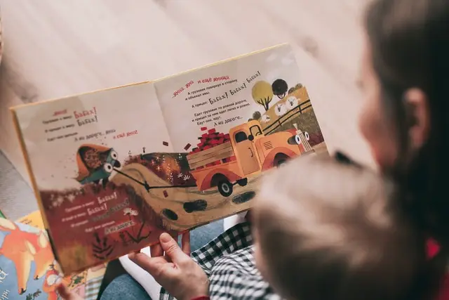 Kid reading a book along with a parent
